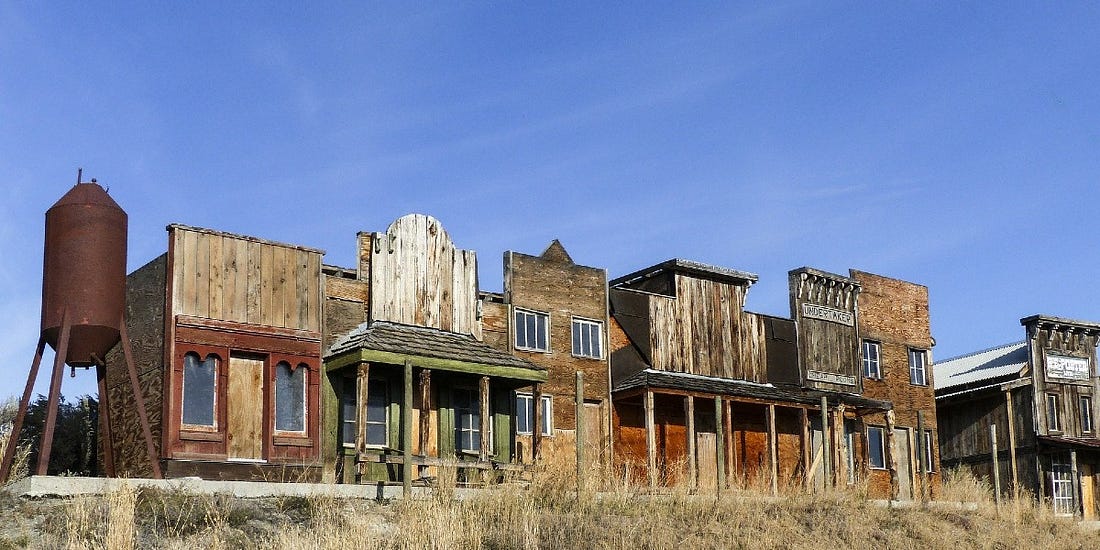 A row of weathered wooden storefronts in a historic western town